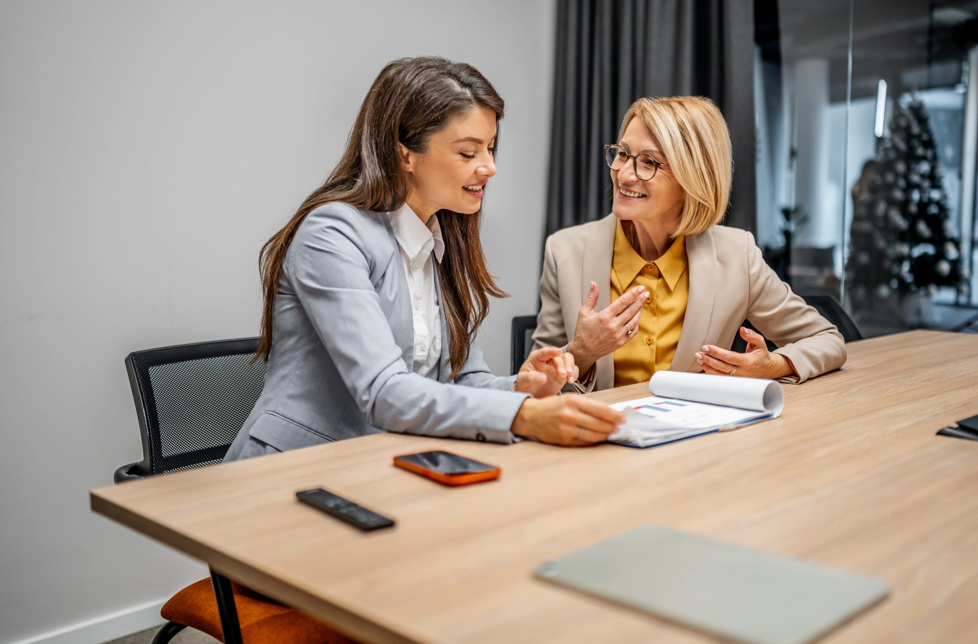 Two women engaged in a business discussion at a table.